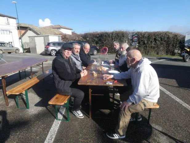 Des convives attablés en plein air lors de la vente de gratin d'andouillette au profit de l'association